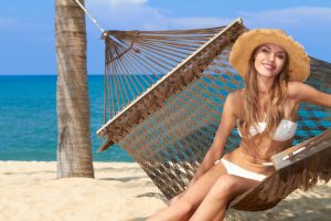 Beautiful woman on the beach sitting on a hammock