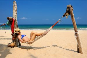Beautiful woman lying in a hammock on a Costa Rica beach enjoying the breast lift with implants procedure she had in Costa Rica